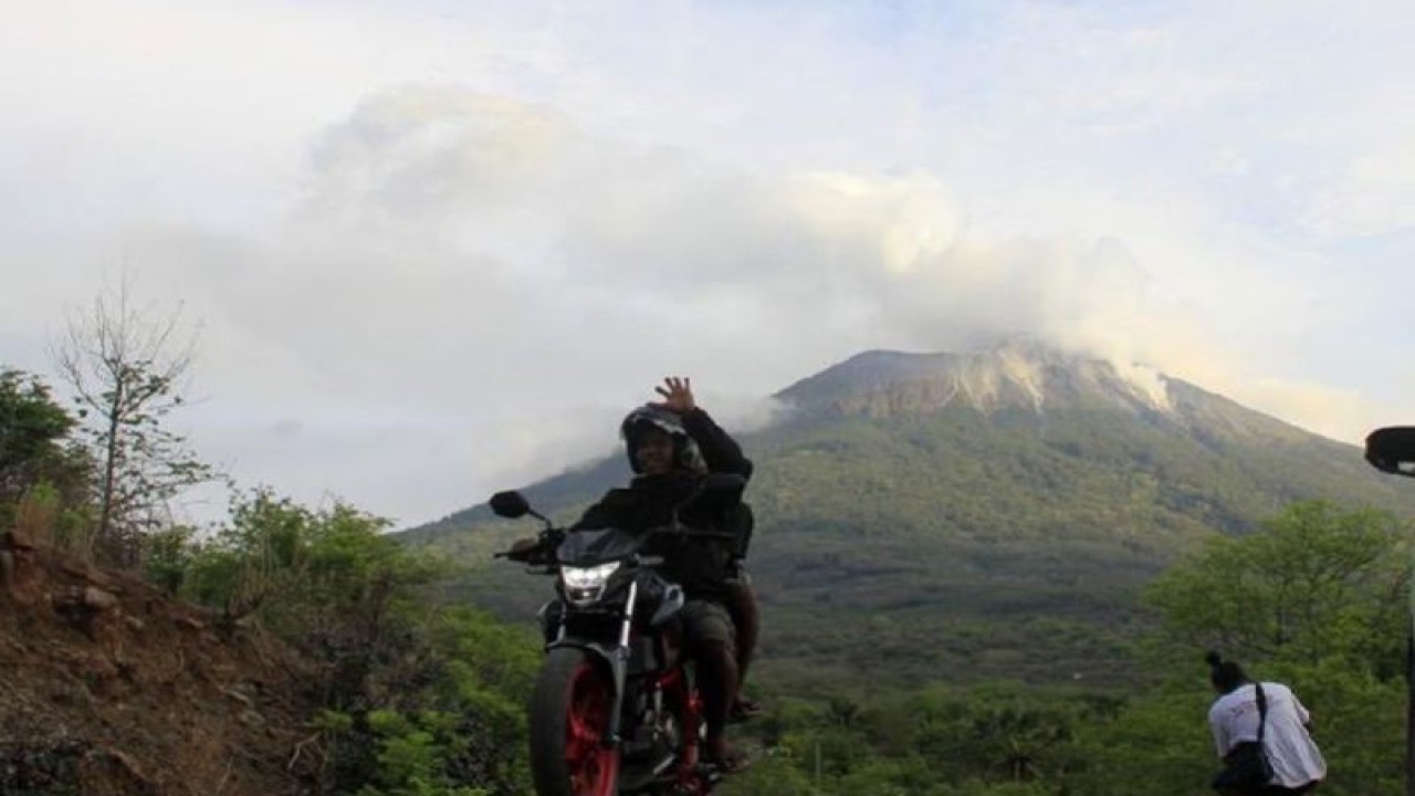 Arsip. Pengendara bermotor melintas di depan gunung api Ile Lewotolok. ANTARA/Kornelis Kaha