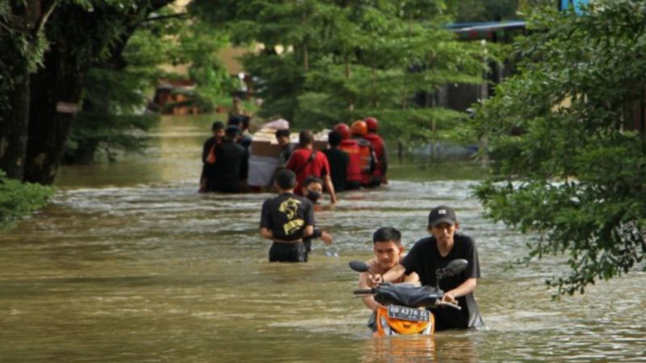 Arsip Foto. Warga menuntun sepeda motor melewati jalanan yang tergenang akibat banjir di Perumnas Antang, Kota Makassar, Provinsi Sulawesi Selatan, Senin (26/12/2022).  ANTARA FOTO/Arnas Padda.