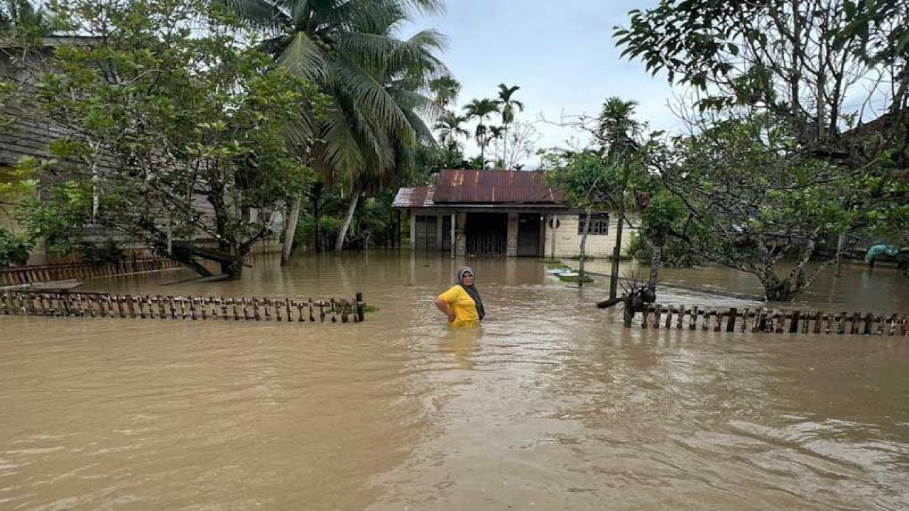 Warga berdiri di depan rumahnya yang terendam banjir di Desa Rayeuk Pange, Kecamatan Pirak Timu, Kabupaten Aceh Utara, Provinsi Aceh, Ahad (22/1/2023). FOTO ANTARA/HO/Dok Warga
