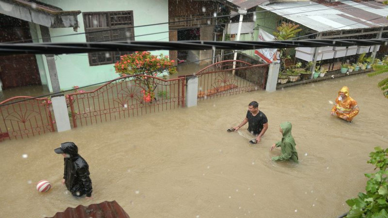 Warga berjalan di kompleks perumahan yang tergenang akibat banjir di Kota Manado, Provinsi Sulawesi Utara, Jumat (27/1/2023). (ANTARA FOTO/ADWIT B PRAMONO)