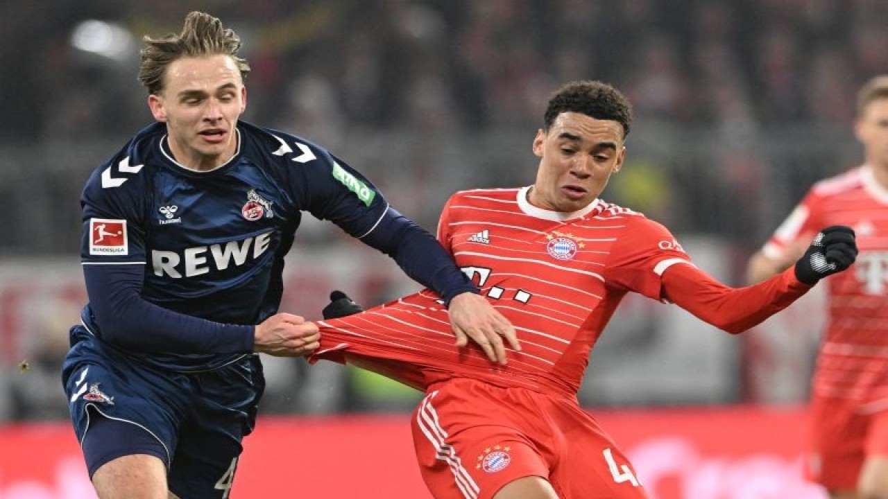 Gelandang Koln Mathias Olesen (kiri) berduel memperebutkan bola dengan gelandang Bayern Muenchen Jamal Musiala pada pertandingan Liga Jerman yang dimainkan di Stadion Allianz Arena, Munich, Rabu (25/1/2023). (ANTARA/AFP/CHRISTOF STACHE)
