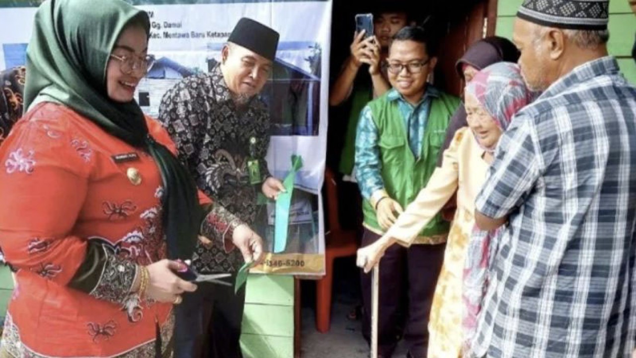 Wakil Bupati Irawati dan Ketua Baznas Kotawaringin Timur Syarifuddin memotong pita menandai penyerahan secara simbolis salah satu bantuan renovasi rumah layak huni di Kelurahan Baamang Hulu Kecamatan Bamaang, Kamis (19/1/2023). (FOTO ANTARA/Norjani)