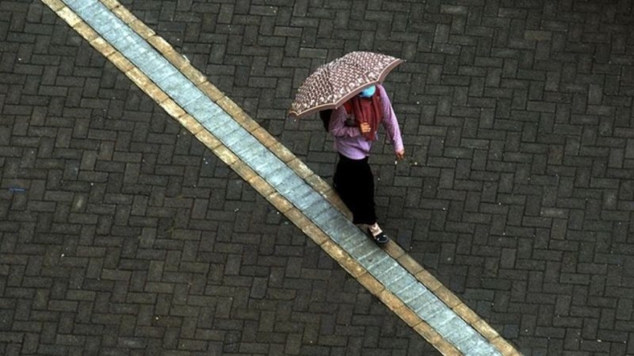 Ilustrasi - Seorang warga berjalan menggunakan payung saat hujan turun di Kota Makassar, Sulawesi Selatan. (ANTARA FOTO/ABRIAWAN ABHE)