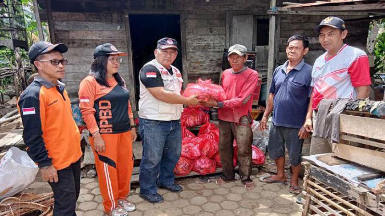 Kasi Kedaruratan dan Logistik BPBD Barito Selatan Suwono didamping Kepala Desa Baru saat menyerahkan bantuan kepada korban yang rumahnya terdampak abrasi di Desa Baru, Jumat (6/1/2023).ANTARA/Bayu Ilmiawan.