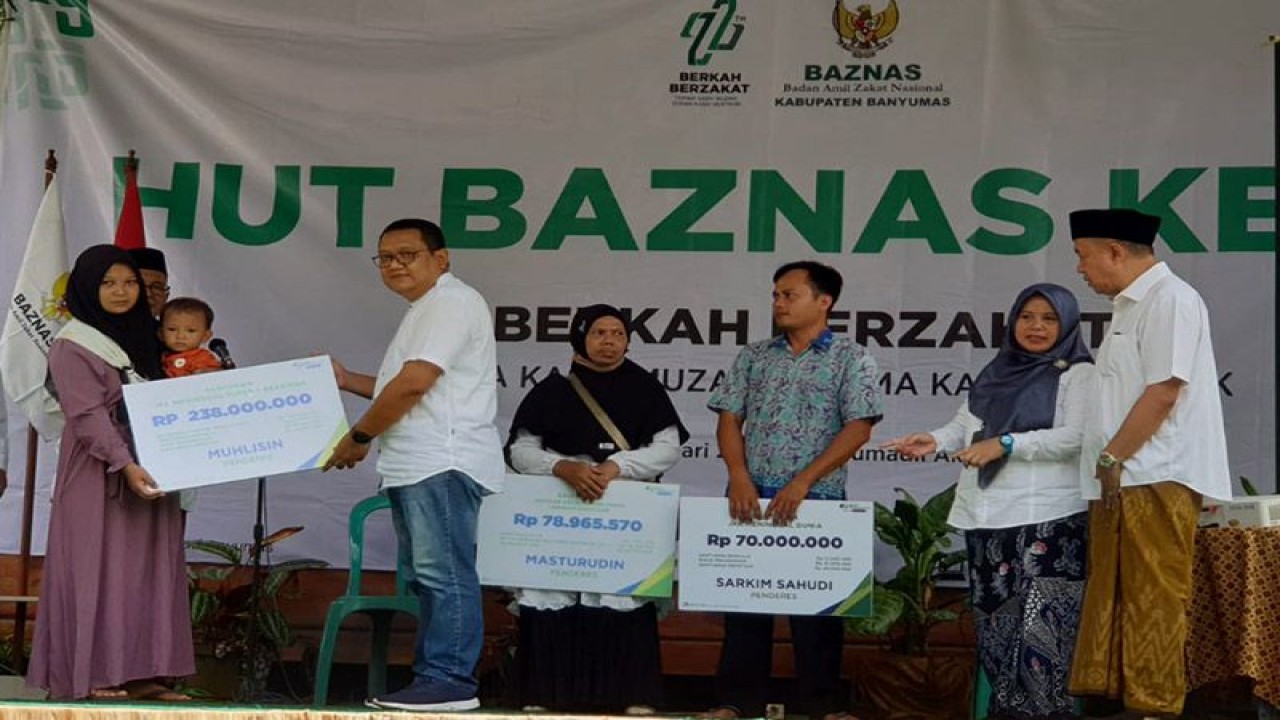 Kepala BPJAMSOSTEK Cabang Purwokerto Antony Sugiarto (dua dari kiri) menyerahkan santunan kepada salah seorang ahli waris penderes dengan disaksikan oleh Wakil Bupati Banyumas Sadewo Tri Lastiono (kanan) di sela Tasyakuran HUT Ke-22 Baznas Tingkat Kabupaten Banyumas di Cilongok, Banyumas, Selasa (17/1/2023). ANTARA/HO-BPJAMSOSTEK Purwokerto