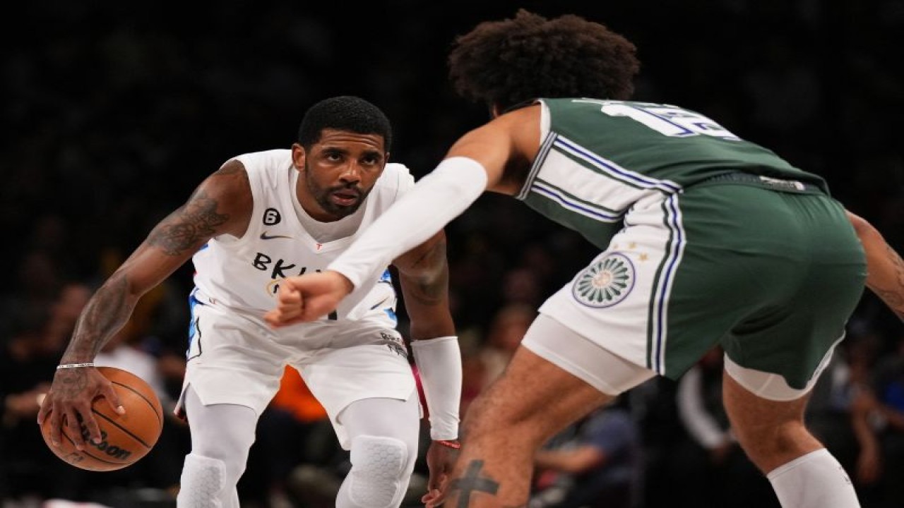 Pebasket Brooklyn Nets Kyrie Irving (kiri) mendribel bola dihadang pebasket Detroit Pistons Isaiah Livers saat pertandingan NBA kedua tim di Barclays Center, New York City, Kamis (26/1/2023) (Getty Images via AFP/MIKE STOBE)