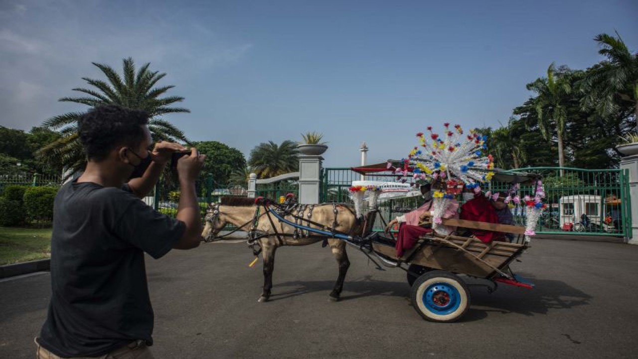 Arsip Foto - Sejumlah warga berfoto dengan menaiki delman di kawasan pintu silang barat Monumen Nasional (Monas), Jakarta, Rabu (20/10/2021). ANTARA FOTO/Aprillio Akbar/hp.