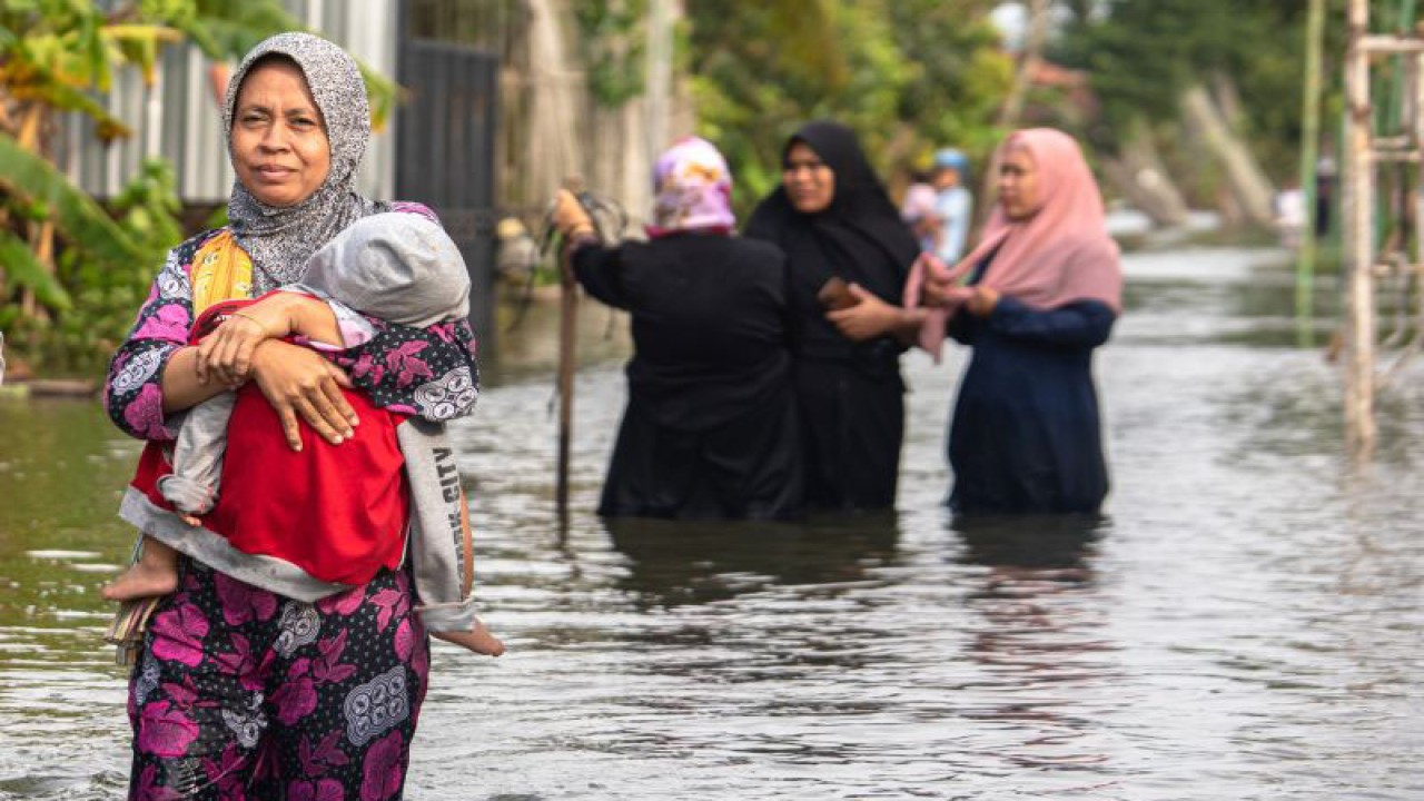 Sejumlah warga menembus banjir yang merendam jalan desa di Desa Prampelan, Kecamatan Sayung, Kabupaten Demak, Jawa Tengah, Selasa, (3/1/2023). ANTARA FOTO/Aji Styawan/foc. (ANTARA FOTO/AJI STYAWAN)