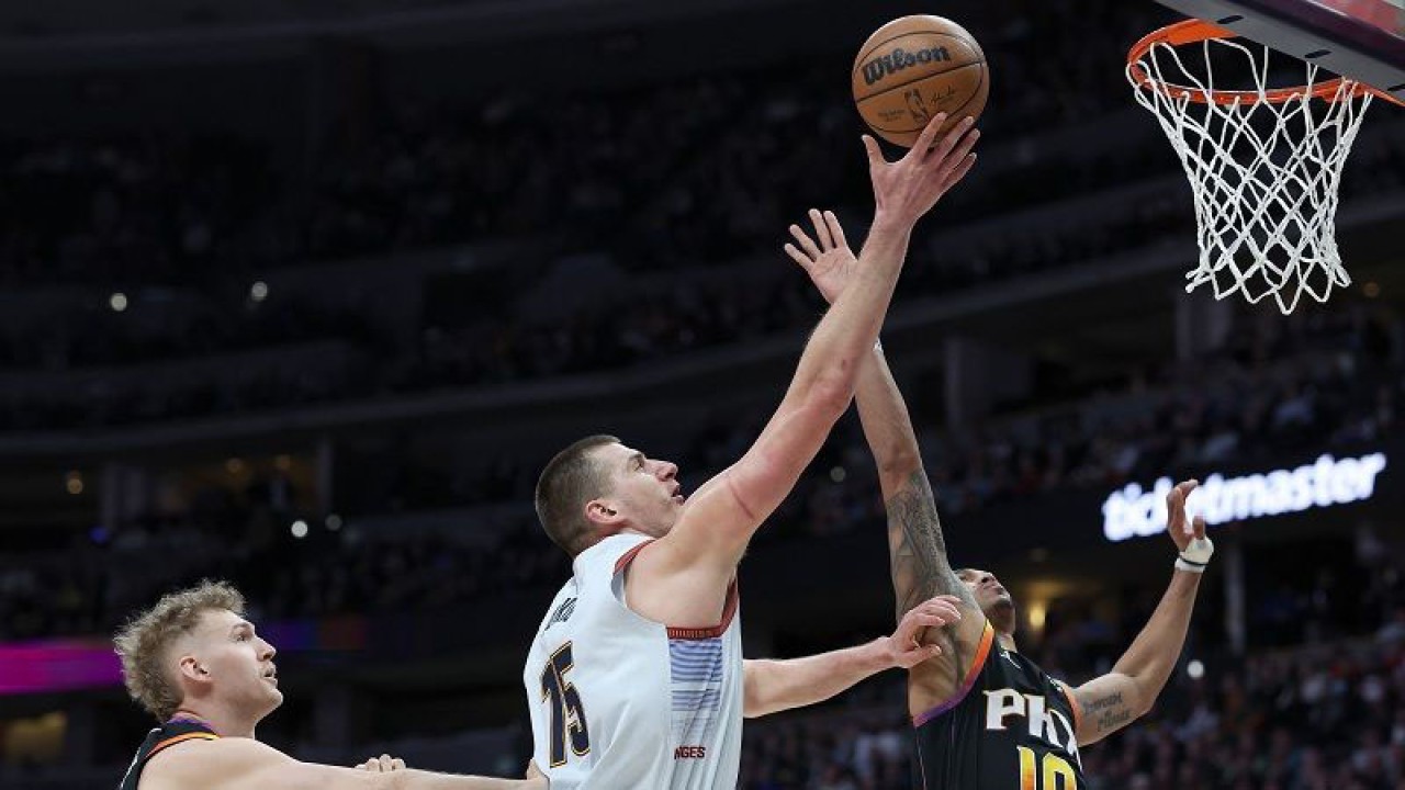 Bintang Denver Nuggets Nikola Jokic (tengah) berusaha mencetak angka di tengah apitan pemain Suns, Damion Lee (kanan) dan Jock Landale, dalam lanjutan NBA di Ball Arena, Colorado, Amerika Serikat, Rabu (11/1/2023) waktu setempat. (ANTARA/AFP/GETTY IMAGES/Matthew Stockman)