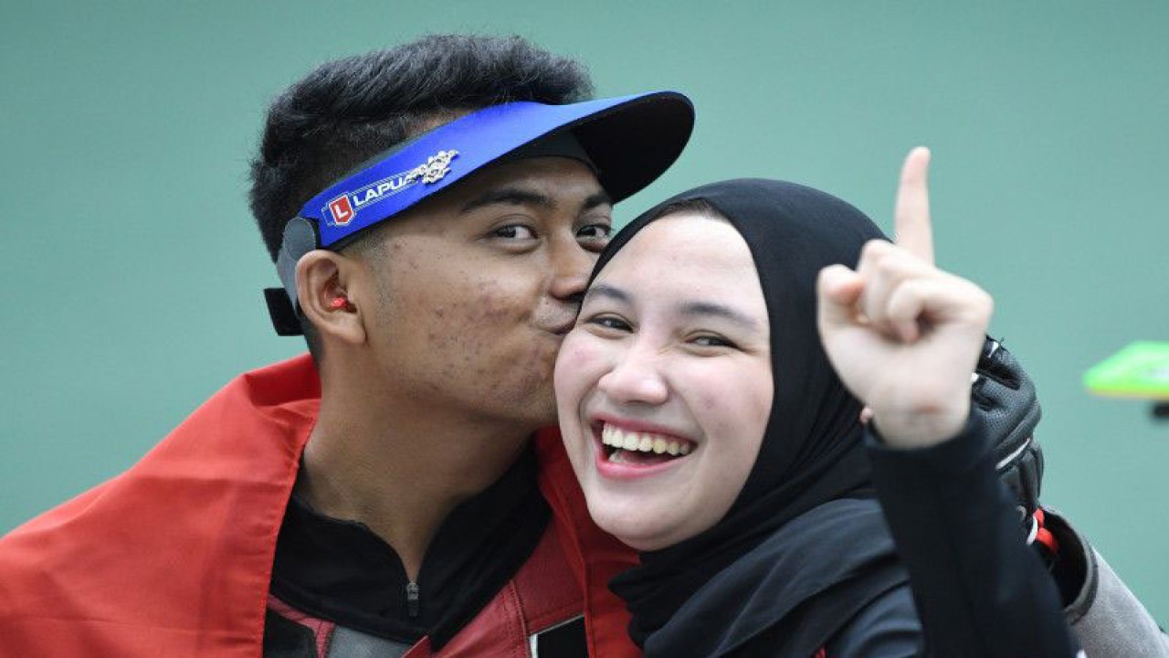 Foto arsip - Petembak Fathur Gustafian (kiri) mencium kekasihnya yang juga petembak peraih medali emas, Dewi Laila Mubarokah (kanan), usai memenangkan nomor 10 meter air rifle (senapan angin) putra menembak SEA Games 2021 Vietnam di Hanoi Sports Training and Competition Center, Hanoi, Vietnam, Selasa (17/5/2022). Fathur meraih medali emas setelah meraih poin terbanyak 247,4 poin. ANTARA FOTO/Aditya Pradana Putra/hp,