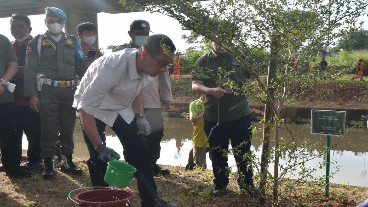 Penjabat Gubernur DKI Jakarta Heru Budi Hartono (tengah) menyiram pohon ketapang kencana saat meninjau kawasan hijau di bawah kolong Tol Becakayu (Bekasi Cawang Kampung Melayu), Jakarta, Jumat (6/1/2023). Kegiatan tersebut untuk memastikan penataan kawasan hijau yang telah dikerjakan sepanjang 2,7 km dari target 5 km di Jakarta terus berjalan sehingga bisa memberi kenyamanan serta kesegaran bagi warga. ANTARA FOTO/Fakhri Hermansyah/nym.