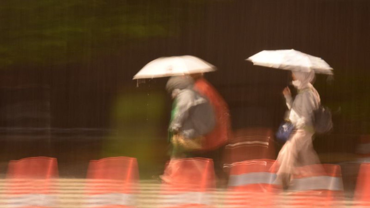 Pekerja menerobos hujan saat pulang dari bekerja di kawasan Rasuna Said, Jakarta, Jumat (4/11/2022). ANTARA FOTO/Indrianto Eko Suwarso/wsj.