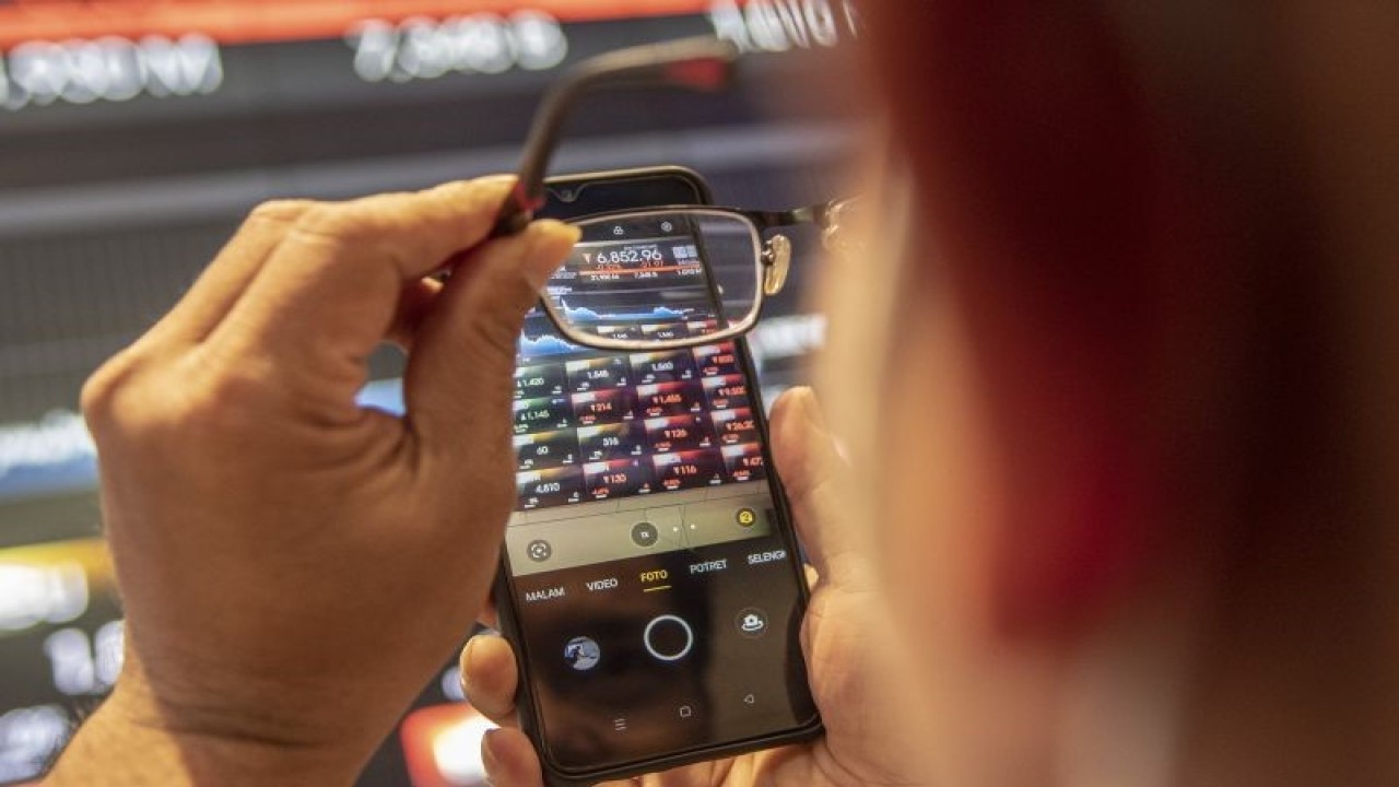 Karyawan mengambil gambar menggunakan ponselnya layar yang menunjukkan pergerakan Indeks Harga Saham Gabungan (IHSG) di Bursa Efek Indonesia, Jakarta, Selasa (24/1/2023). ANTARA FOTO/Muhammad Adimaja/aww. (ANTARA FOTO/MUHAMMAD ADIMAJA)