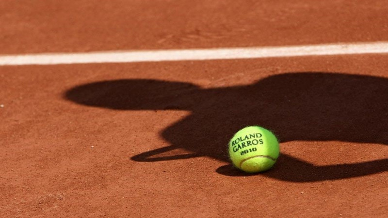 ilustrasi - Bola resmi turnamen tenis dengan bayang-bayang seorang pemain tenis diatas tanah. ANTARA/Shutterstock/pri.