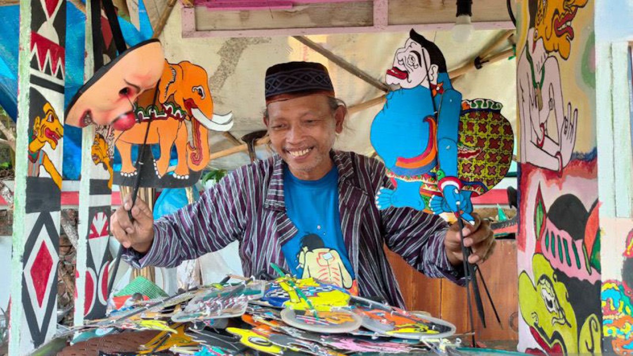 Iskandar dan wayang uwuh karyanya yang terbuat dari sampah kertas dan botol plastik bekas minuman (17/1/2023) (ANTARA/Eka AR)