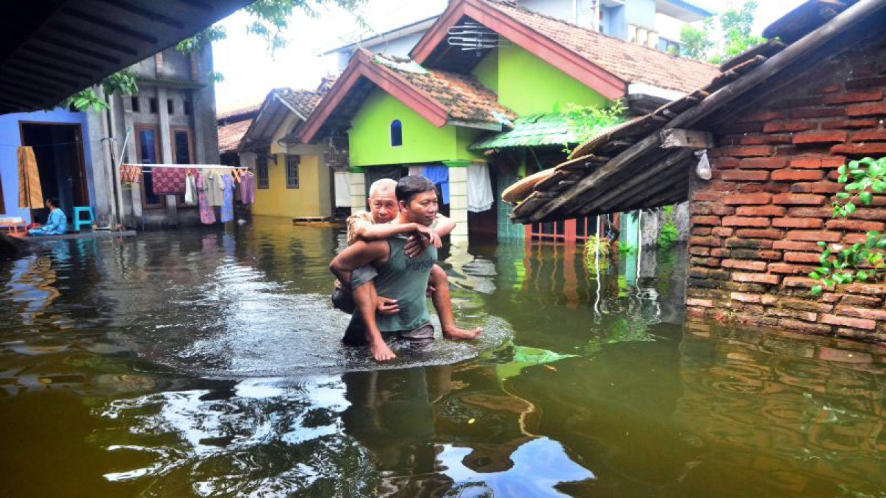 Warga melewati halaman rumah yang terendam akibat banjir di Dusun Gendok, Jati Wetan, Jati, Kudus, Jawa Tengah, Kamis (5/1/2023). (ANTARA FOTO/YUSUF NUGROHO)