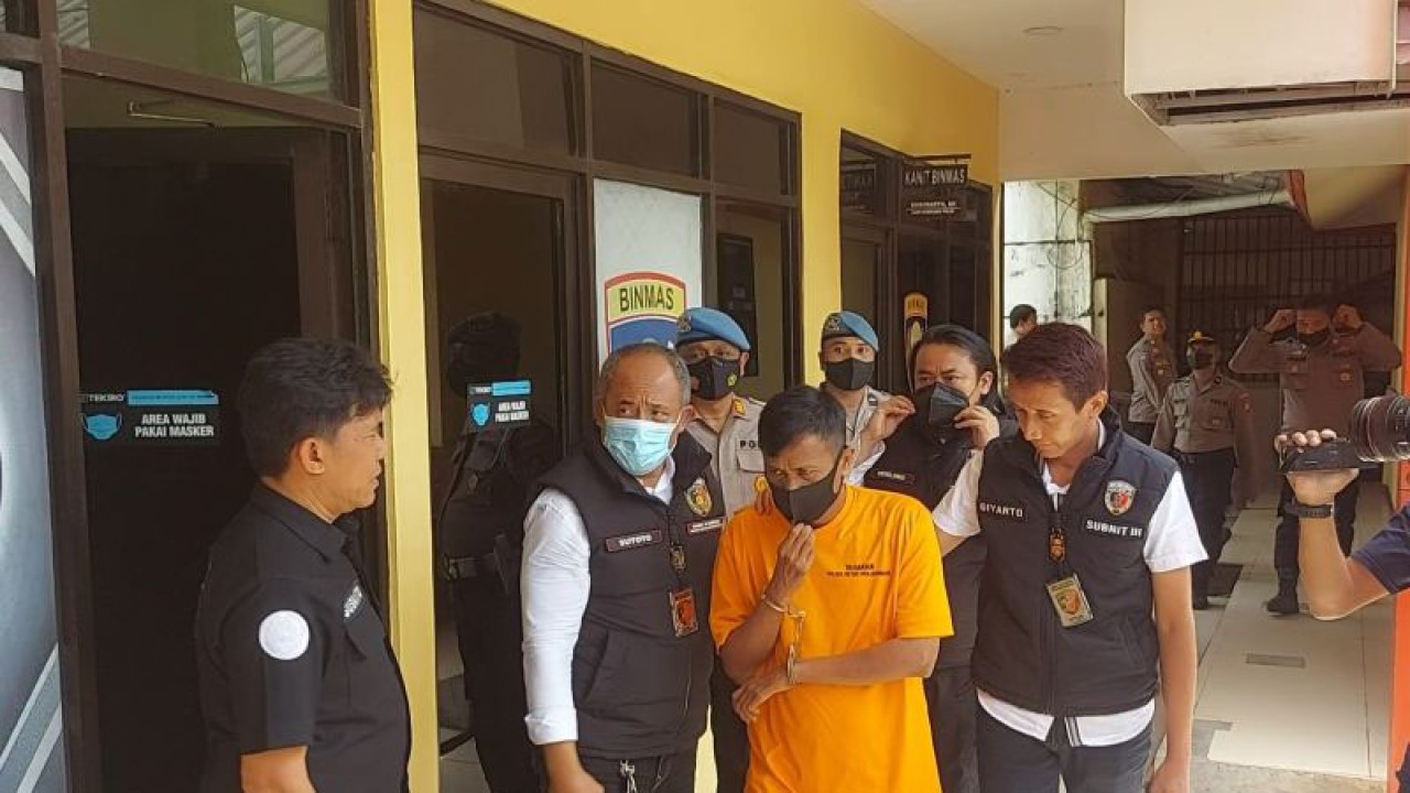 Tersangka pembakar orang di bantaran Kali Angke, Pejagalan, Penjaringan, Jakarta Utara, berinisial MR (43) berjalan dikawal sejumlah petugas Kepolisian Sektor Metro Penjaringan, Jakarta Utara, dengan tangan terborgol dan menggunakan baju tahanan oranye sebelum konferensi pers di Markas Polsek Metro Penjaringan, Jakarta Utara, Senin (9/1/2023). ANTARA/Abdu Faisal
