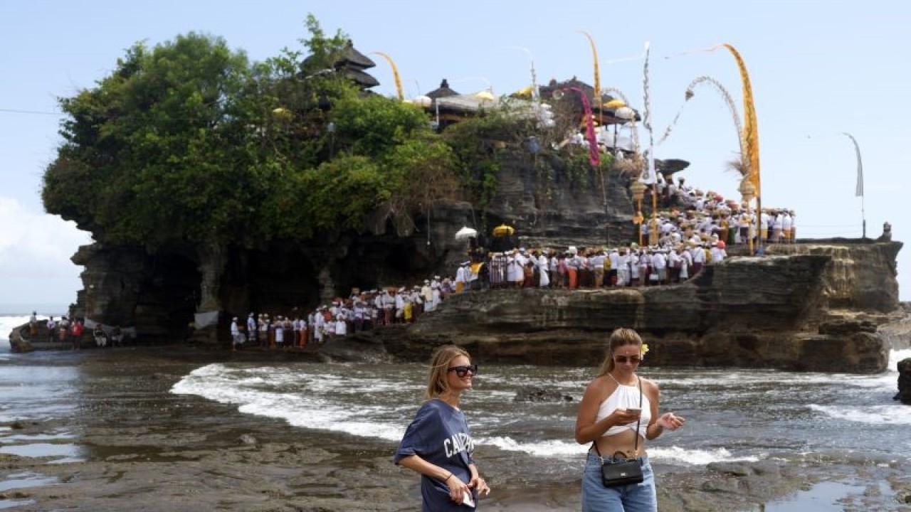 Wisatawan menikmati suasana objek wisata Tanah Lot, di Tabanan, Bali, Jumat (20/1/2023). Situs perjalanan TripAdvisor melalui penghargaan TravelersÕ Choice Award 2023 menobatkan Bali sebagai destinasi wisata terpopuler kedua di dunia. ANTARA FOTO/Nyoman Hendra Wibowo/aww.