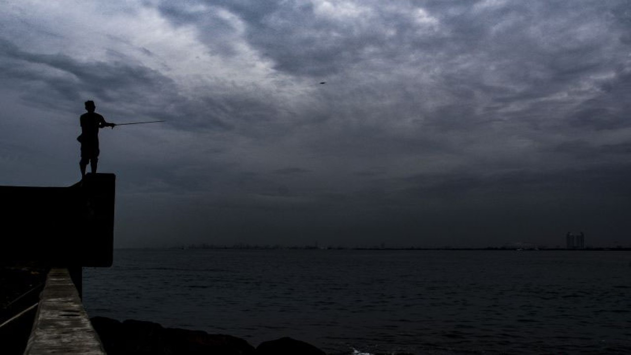 Seorang warga memancing ikan di atas tanggul laut Pelabuhan Muara Baru, Jakarta, Rabu (28/12/2022). ANTARA FOTO/SULTHONY HASANUDDIN)