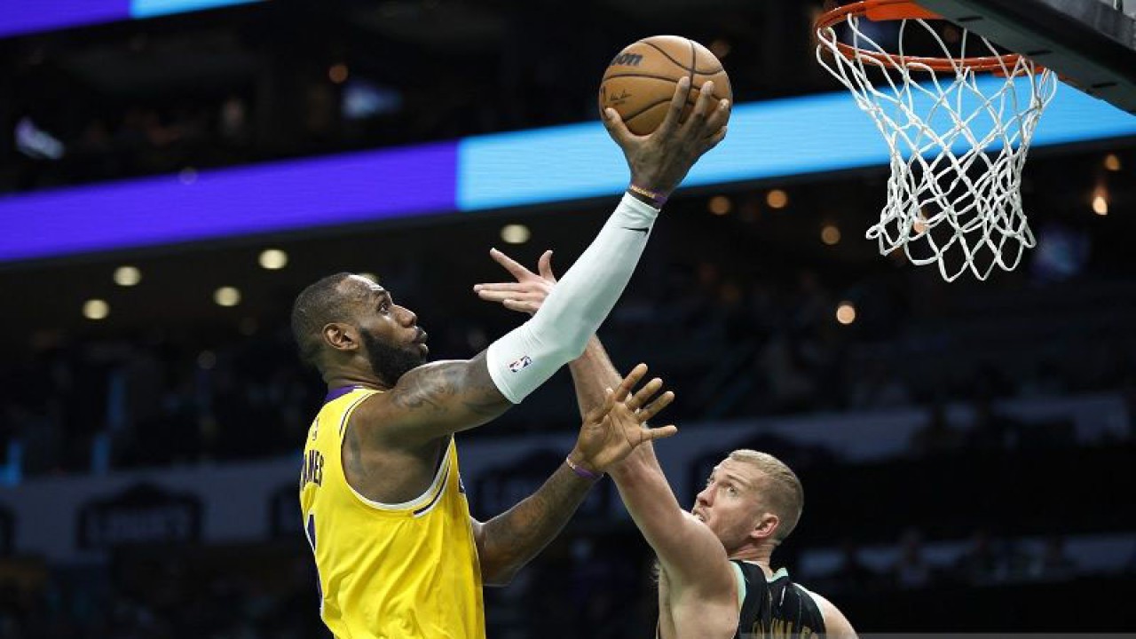 Megabintang Los Angeles Lakers LeBron James (kiri) melewati hadangan pemain Charlotte Hornets Mason Plumlee untuk mencetak angka dalam gim lanjutan NBA di Spectrum Center, Carolina Utara, Amerika Serikat, Senin (2/1/2023) waktu setempat. (ANTARA/AFP/GETTY IMAGES/Jared C. Tilton)