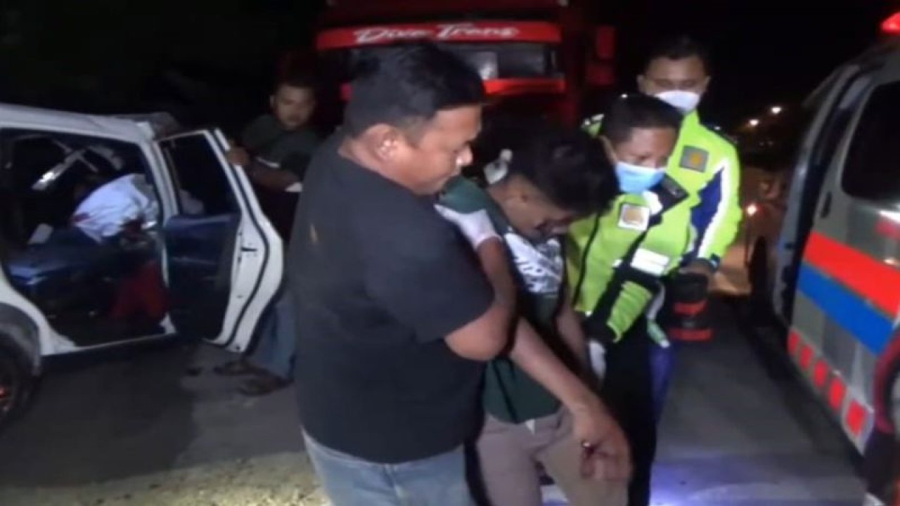 Petugas Polres Ngawi dibantu warga mengevakuasi korban kecelakaan mobil "low MPV" Mobilio menabrak truk tronton di Ring Road Ngawi masuk Desa Kandangan Kabupaten Ngawi, Jawa Timur, Kamis (12/1/2022). (ANTARA/Louis Rika)
