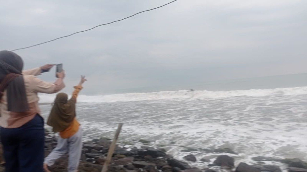 Dua wisatawan di pesisir Pantai Anyer mengarah pandangan menuju Gunung Anak Krakatau yang berlokasi di Selat Sunda tampak tertutup kabut. ANTARA/Mansur