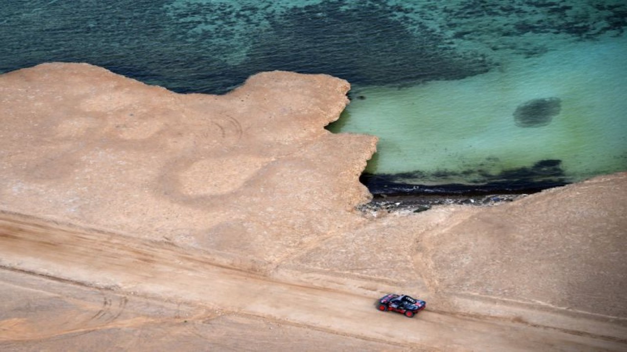 Pebalap Spanyol Carlos Sainz dan co-driver Lucas Cruz dari tim Audi menjalani prolog Dakar 2023 di pesisir Laut Merah, Yanbu, Arab Saudi. (31/12/2022) (AFP/FRANCK FIFE)