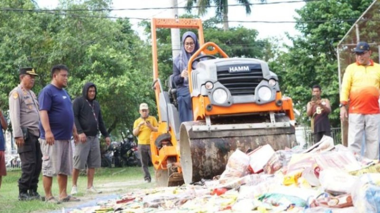 Bupati Luwu Utara Indah Putri Indriani saat mengemudikan kendaraan alat berat untuk memusnahkan produk makanan kedaluarsa. ANTARA/HO/Pemkab Lutra