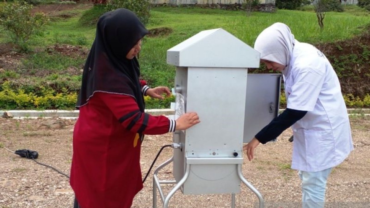 Kepala Bidang Penataan, Peningkatan Kapasitas Lingkungan  Dinas Perumahan, Kawasan Permukiman, Lingkungan Hidup dan Perhubungan Solok Selatan, Erna Wijayanti (kiri) bersama petugas UPTD Laboratorium Lingkungan Hidup mengecek alat ukur High Volume Air Sampler (HVAS) di BBI Bukit Malintang, Kecamatan Sangir, Solok Selatan, Minggu (15/1). (ANTARA/Joko Nugroho)