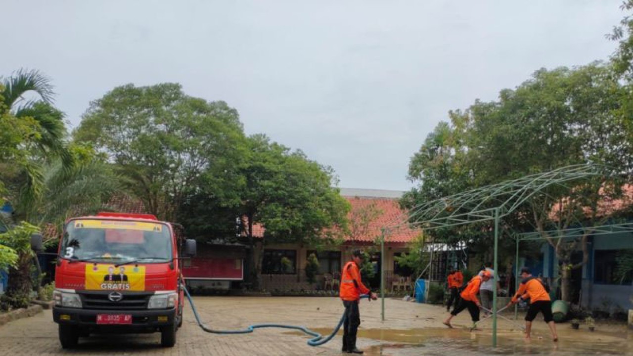 Petugas BPBD Pemkab Pamekasan membersihkan halaman SMP Negeri 1 Pamekasan usai banjir merendam sekolah itu pada 31 Desember 2022. (ANTARA/Abd. Aziz)
