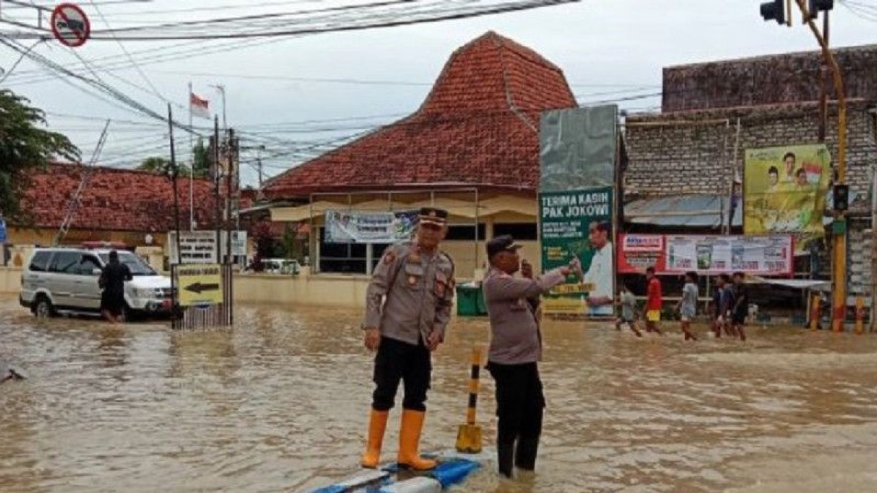 Petugas Polres Sampang mengatur arus lalu lintas di lokasi banjir di Kota Sampang, Jawa Timur, Minggu (1/1/2023). ANTARA/HO-Polres Sampang