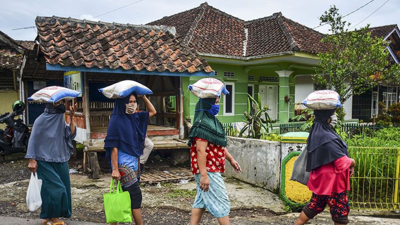 Warga berjalan beriringan usai mengambil bantuan sembako, bantuan tunai, dan bantuan dari Program Keluarga Harapan (PKH) di Kantor Kelurahan Maleber, Kabupaten Ciamis, Provinsi Jawa Barat, Selasa (29/11/2022). (ANTARA FOTO/ADENG BUSTOMI)