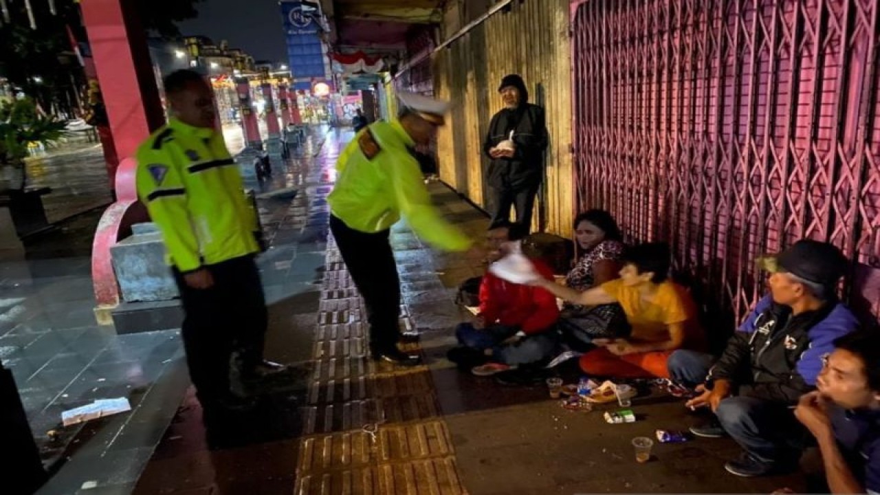 Petugas Satlantas Polresta Bogor Kota saat memberikan makanan kepada pemulung dan tukang becak yang tidak memiliki tempat tinggal di sekitar jalur sistem satu arah (SSA) pada Selasa (10/1/2022). ANTARA/HO/Polresta Bogor