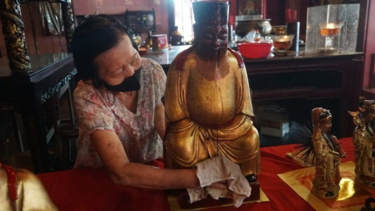 Seorang perempuan membersihkan rupang dari sisa kotoran debu untuk menyambut Imlek 2023 di Kelenteng Po An Thian, Selasa (17/1/2023). (ANTARA/HO-Humas Pemkot Pekalongan)