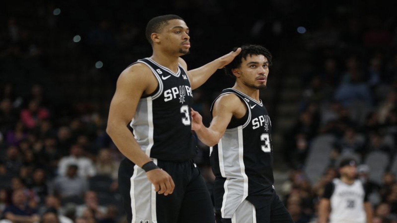 Pebasket San Antonio Spurs Tre Jones (kanan) disalami rekannya Keldon Johnson setelah tim mereka memenangi pertandingan NBA kontra Brooklyn Nets di AT&T Center, San Antonio, Texas., Selasa (17/1/2023) (Getty Images via AFP/RONALD CORTES)