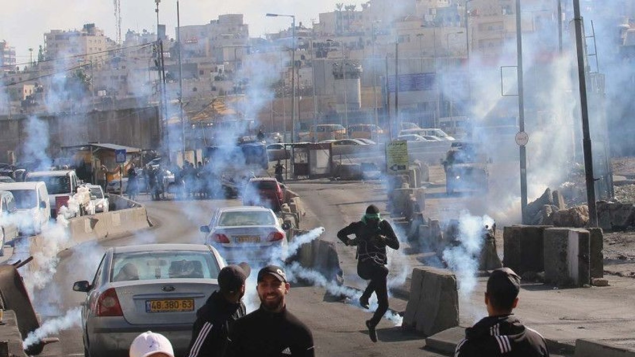 Arsip - Para warga Palestina pengunjuk rasa berlarian untuk berlindung dari tabung gas air mata yang ditembakkan oleh pasukan keamanan Israel dalam bentrokan di pos pemeriksaan Qalandia dekat Kota Ramallah di Tepi Barat (27/12/2022). ANTARA FOTO/Xinhua/Nidal Eshtayeh/aww.