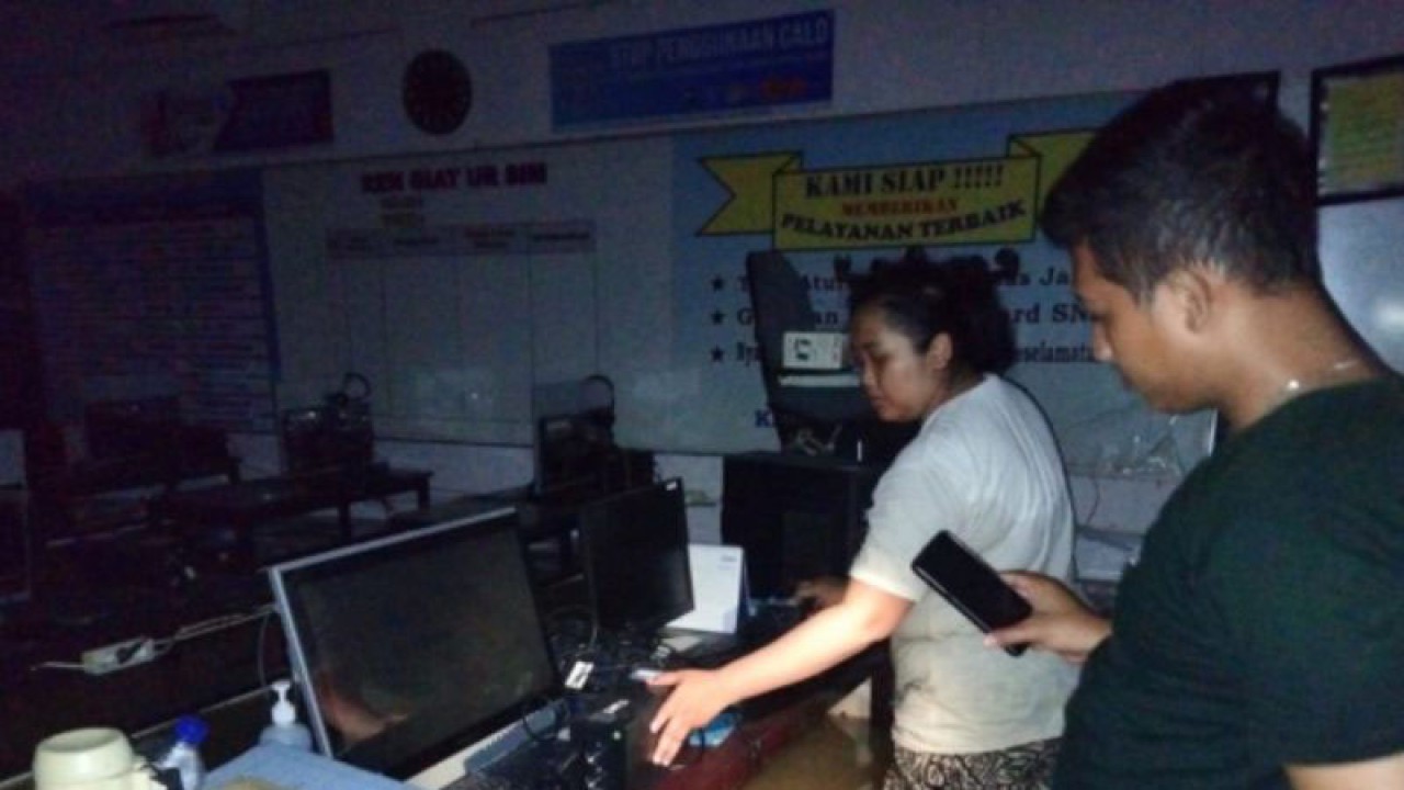 Petugas menunjukkan komputer di kantor pembuatan SIM Sampang yang tergenang banjir akibat banjir luapan Sungai Kalikamuning yang menggenangi wilayah itu dan hingga Senin (2/1/2023) masih berlangsung. (ANTARA/HO-Polres Sampang)