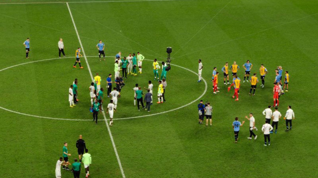 Para pemain tim nasional Ghana (kiri) dan Uruguay berkumlul di tengah lapangan Stadion Al Janoub, Al Wakra, Qatar, Jumat (2/2/2022) (ANTARA/Gilang Galiartha)