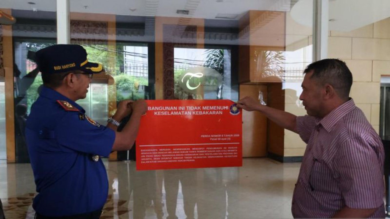 Petugas Dinas Gulkarmat DKI menurunkan stiker bertuliskan gedung yang semula tidak memenuhi standar keselamatan kebakaran di Hotel Treva di Jakarta, Rabu (18/1/2023). ANTARA/HO-Pemprov DKI Jakarta