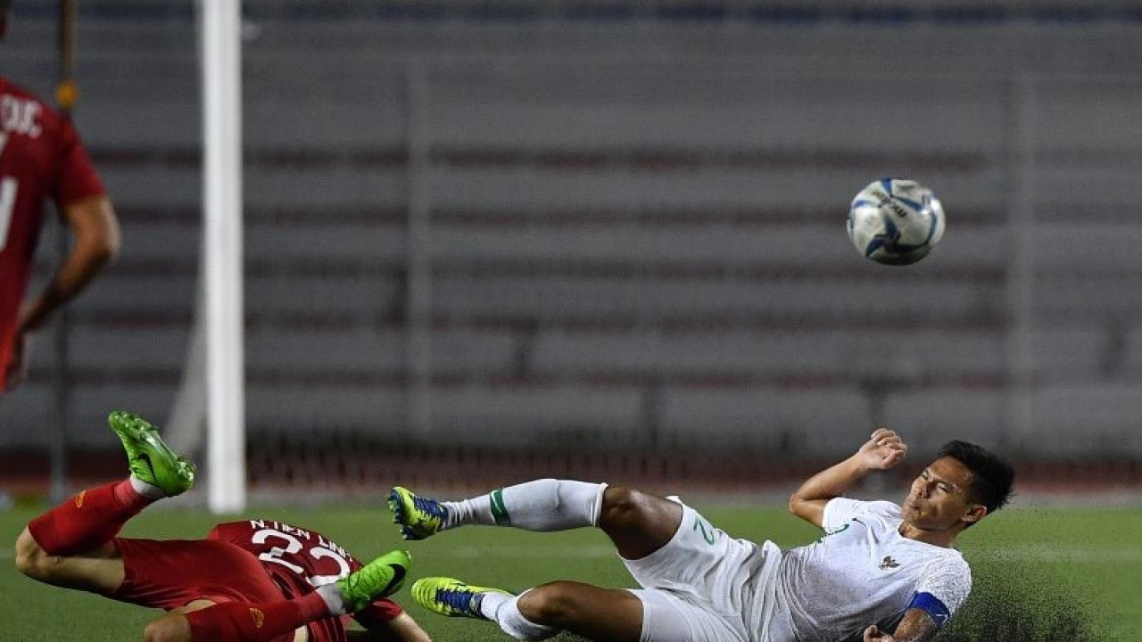 Pemain Timnas U-22 Indonesia Andy Setyo (kanan) terjatuh saat berebut bola dengan pemain Timnas Vietnam Nguyen Tien Linh dalam pertandingan Grup B SEA Games 2019 di Stadion Rizal Memorial, Manila, Filipina, Minggu (1/12/2019). . ANTARA FOTO/Sigid Kurniawan/ama. (ANTARA FOTO/SIGID KURNIAWAN)