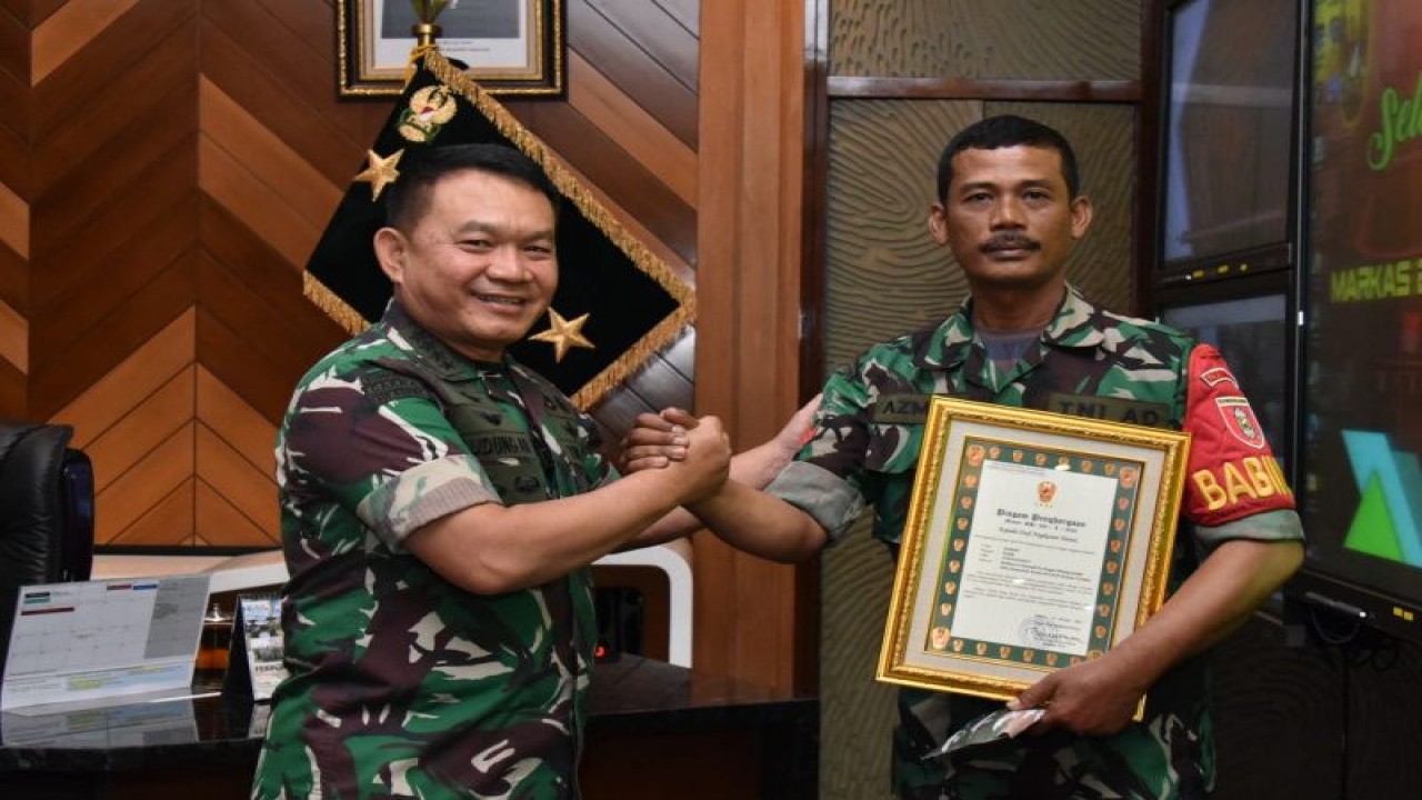 Kepala Staf TNI Angkatan Darat (Kasad) Jenderal TNI Dudung Abdurachman (kiri) menyerahkan plakat apresiasi kepada prajurit Babinsa Koramil 02/Sungai Pinang Kodim 0901/Samarinda, Kopka Azmiadi, yang viral karena menggadaikan sepeda motornya demi kelancaran arus lalu lintas dalam pertemuan di Markas Besar Angkatan Darat, Jakarta, Selasa (24/1/2023). (ANTARA/HO-Dispenad)