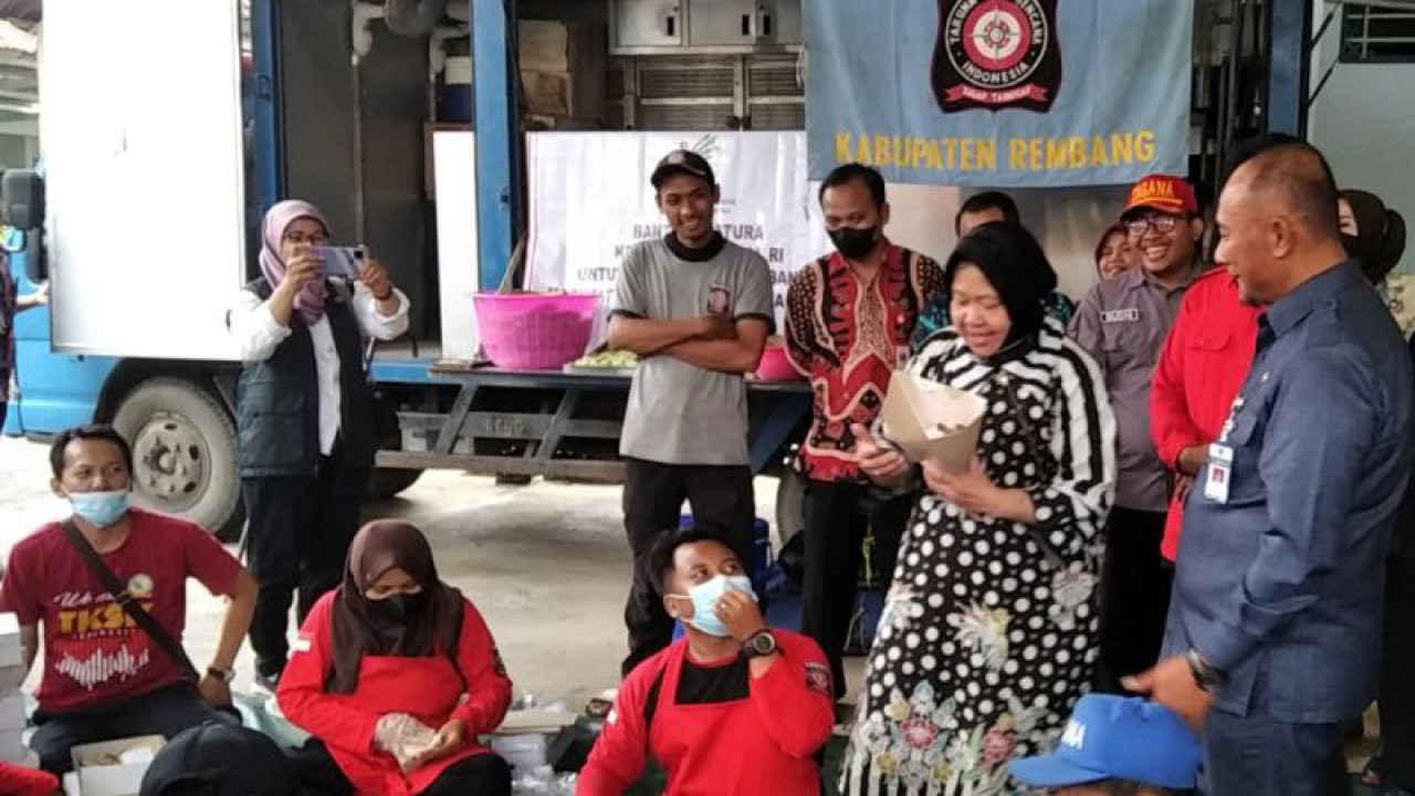 Menteri Sosial (Mensos) Tri Rismaharini didampingi Penjabat Bupati Pati Henggar Budi Anggoro​​​​​​​ saat mencoba ikut membungkus makanan di sela-sela mengecek dapur umum di kantor Margo Laras Pati, Jawa Tengah, Jumat (6/1/2023). (ANTARA/Akhmad Nazaruddin Lathif)