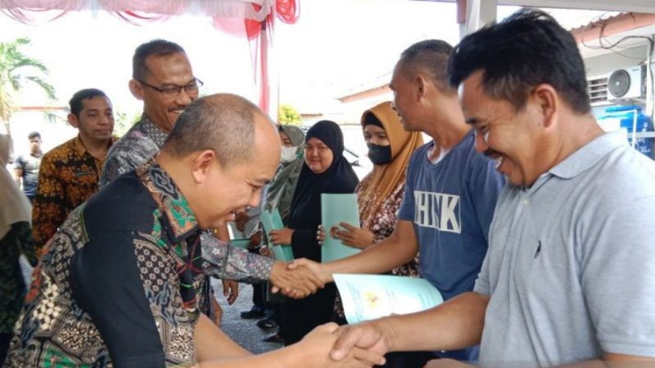 Wali Kota Pangkalpinang Maulan Aklil (kiri) menyerahkan sertifikat tanah pogram PTSL kepada warga Kecamatan Bukitintan. (ANTARA/HO-Humas Pemkot Pangkalpinang)