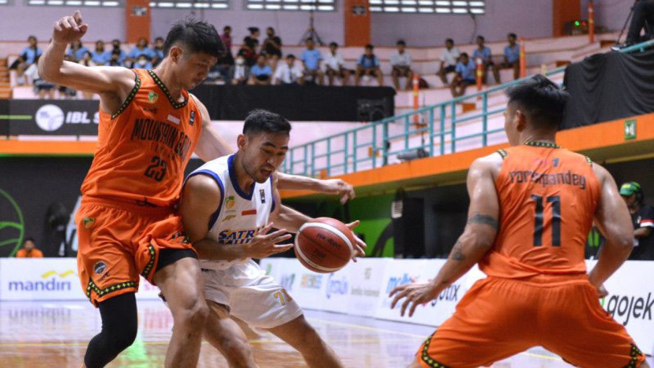 Pebasket Satria Muda Pertamina Jakarta Widyanta Putra Teja (tengah) berusaha melewati hadangan pebasket Mountain Gold Timika Ruslan (kiri) dan Andre Rorimpandey (kanan) saat pertandingan Indonesian Basketball League (IBL) 2023 di GOR Merpati, Denpasar, Bali, Senin (16/1/2023). ANTARA FOTO/Fikri Yusuf/rwa (ANTARA FOTO/FIKRI YUSUF)