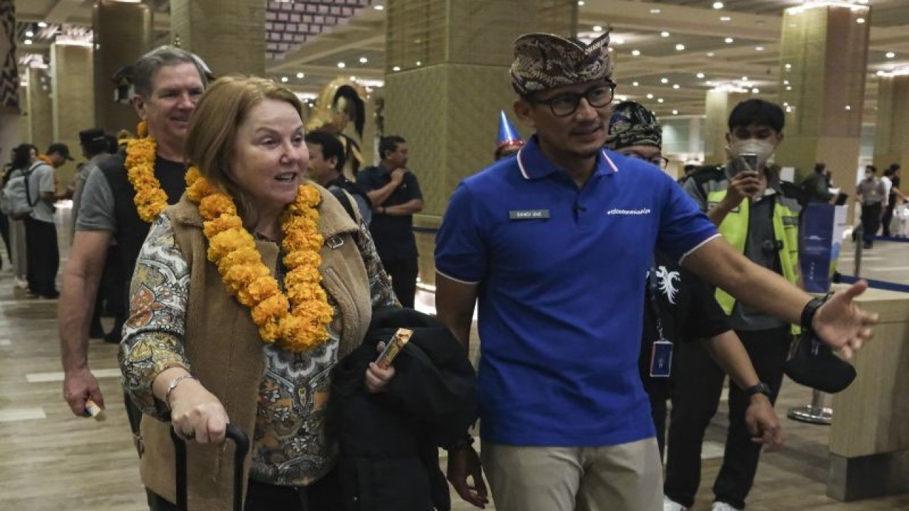 Menteri Pariwisata dan Ekonomi Kreatif (Menparekraf) Sandiaga Salahuddin Uno (kanan) berbincang dengan penumpang pesawat yang tiba pertama di Terminal Kedatangan Internasional pada pergantian Tahun Baru 2023 di Bandara I Gusti Ngurah Rai, Badung, Bali, Minggu (1/1/2023). Sebanyak 273 penumpang pesawat Korean Air yang terbang dari Bandara Internasional Incheon, Korea Selatan tersebut tiba pertama di Bandara I Gusti Ngurah Rai pada Tahun Baru 2023. ANTARA FOTO/Nyoman Hendra Wibowo/foc.