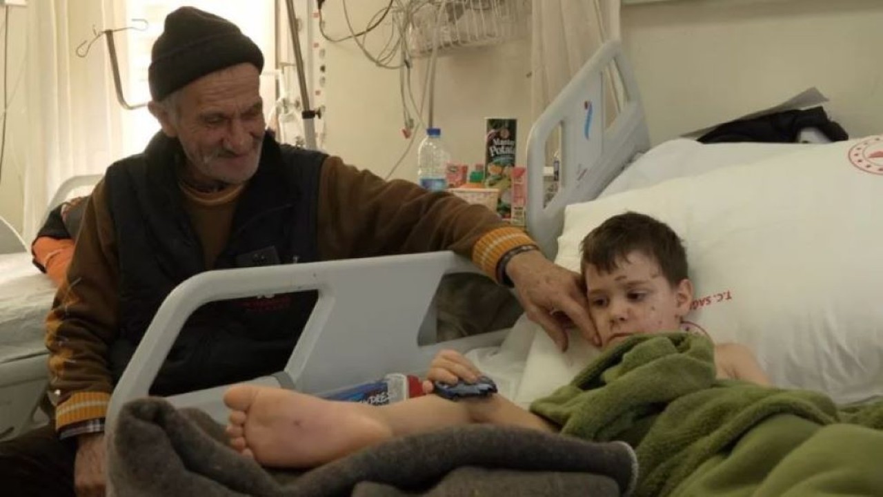 Aras terkulai lemas di ranjang rumah sakit ditemani sang kakek, Mehmet. (BBC)
