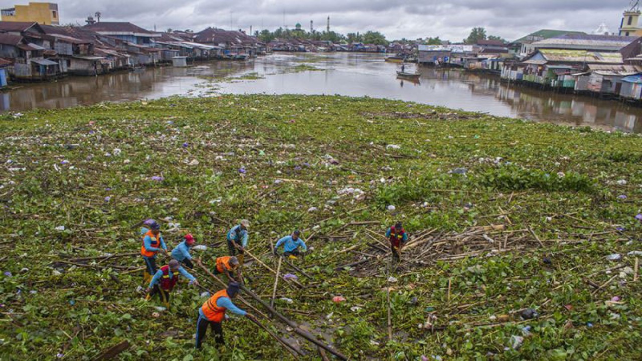 Sejumlah petugas dari Dinas PUPR Kota Banjarmasin membersihkan tumpukan sampah yang menutupi Sungai Martapura di Banjarmasin, Kalimantan Selatan, Rabu (1/2/2023). ANTARA FOTO/Bayu Pratama S/rwa.
