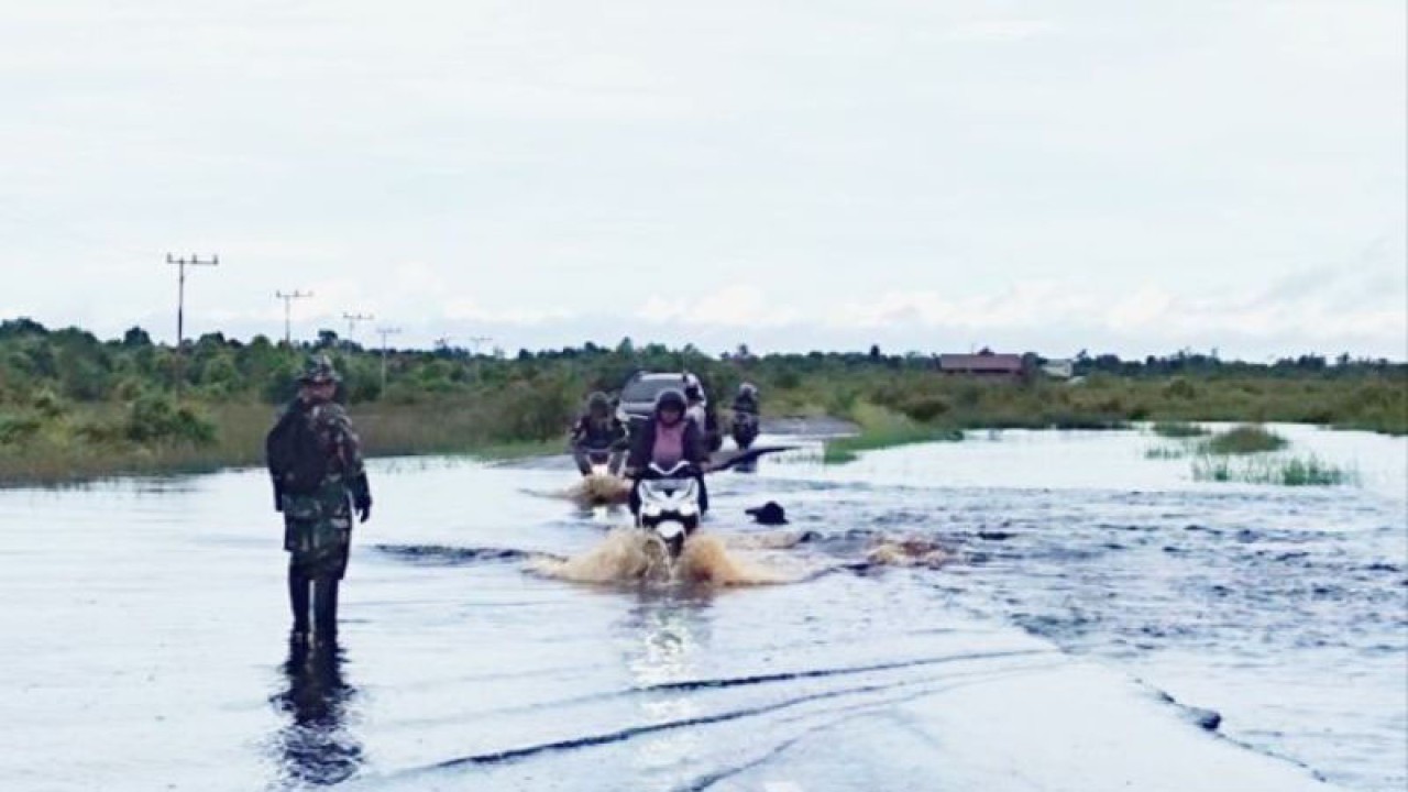 Warga melintasi jalan yang tergenang banjir di wilayah Kelurahan Petuk Katimpun, Kota Palangka Raya, beberapa waktu lalu. (ANTARA/Rendhik Andika)