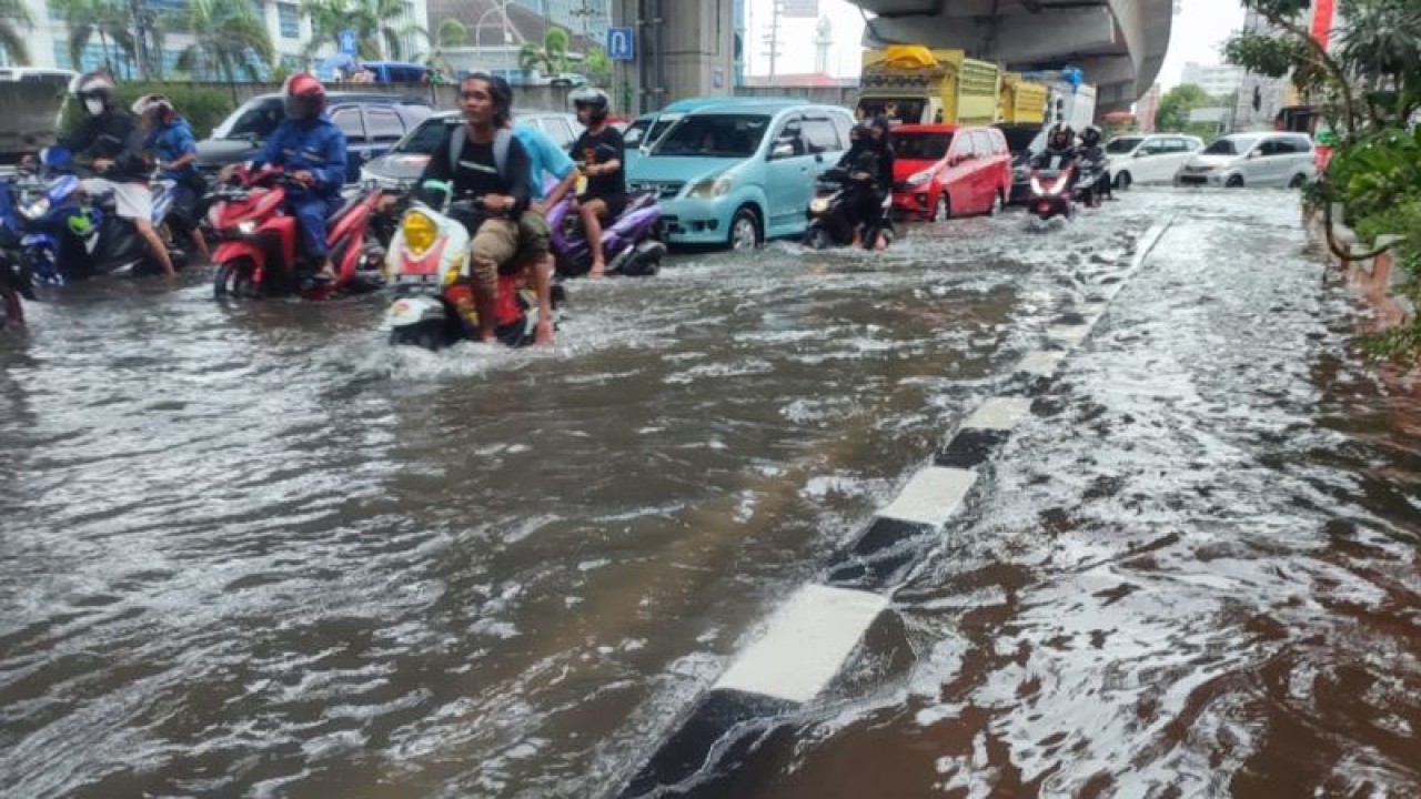 Sejumlah pengendara motor menerobos banjir di jalan protokol Jalan Andi Pangeran Pettarani yang terlihat macet parah saat tergenang air di Makassar, Sulawesi Selatan, Senin (13/2/2023). ANTARA/Darwin Fatir.