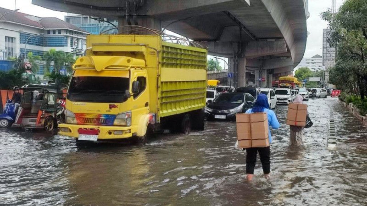 Dua pejalan kaki menerobos banjir yang menggenangi Jalan Andi Pangeran Pettarani, Makassar, Sulawesi Selatan. ANTARA/Darwin Fatir.